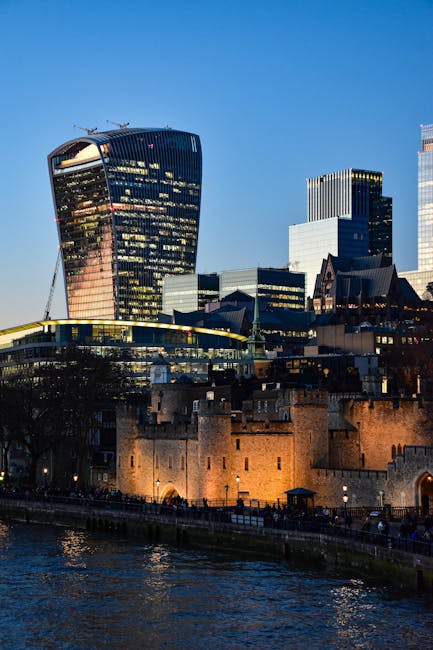 A detailed view of the Tower of London, an historic stone fortress with high stone walls, four prominent towers topped with conical roofs, and crenellated battlements, situated on the north bank of th